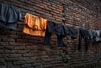 Low angle view of clothes drying against brick wall