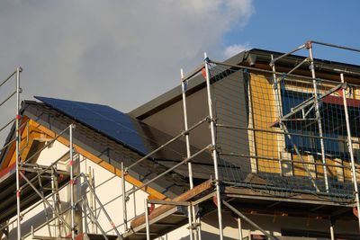 A house is completely scaffolded and. on the roof solar modules have already been installed  