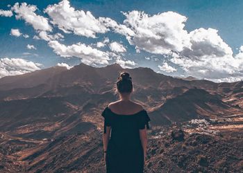 Rear view of man standing on mountain against sky