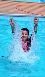 Woman splashing water while swimming in pool