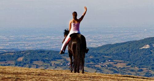 Rear view of woman with arms raised against sky