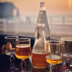 Close-up of wine glasses on table at sunset