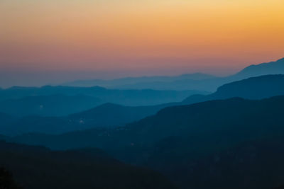 Scenic view of silhouette mountains against orange sky