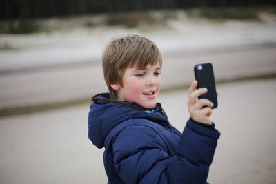 Close-up of boy photographing with mobile phone