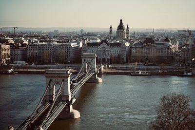 Bridge over river in city against clear sky