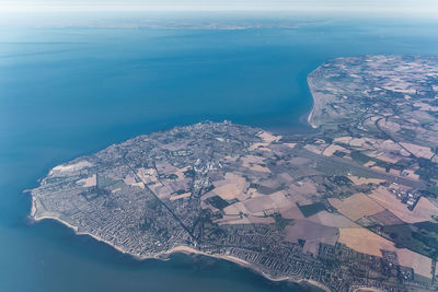 Aerial view of city by sea against sky