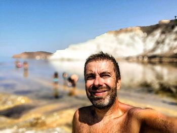 Portrait of man smiling at beach against sky