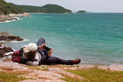 Man lying on beach by sea against sky