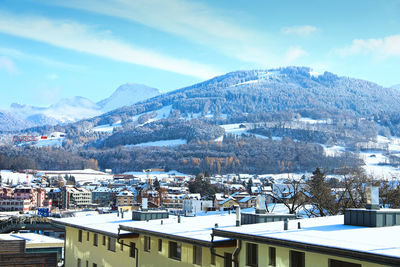 Aerial view of townscape and snowcapped mountains against sky