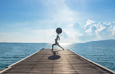 Man on pier over sea against sky