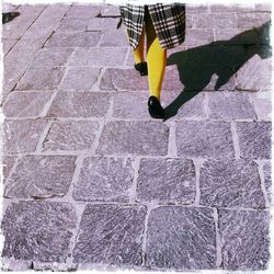 Low section of woman walking on cobbled footpath