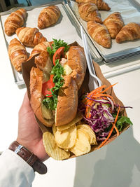 Main meal, meat sandwich with fries, croissant background.