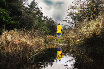 Rear view of man standing by plants against sky