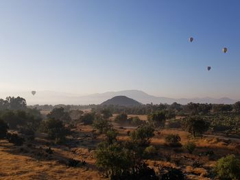 Hot air balloon flying over landscape against clear sky