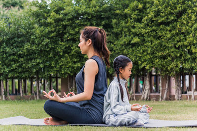 Side view of mother and daughter meditation at park