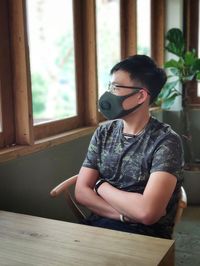 Man wearing mask while sitting on table at restaurant