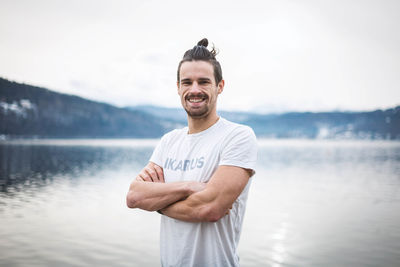 Portrait of young man standing against water