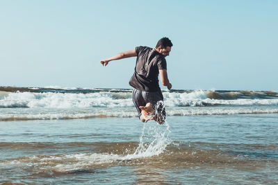 Full length of young man jumping in sea