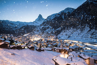 Aerial view of townscape and snowcapped mountains against sky