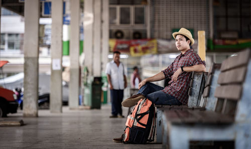 Side view of male tourist sitting on bench in city