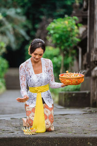 Portrait of young woman standing by plants