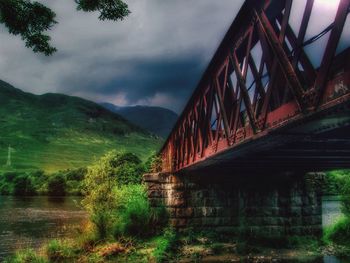 Bridge over river against cloudy sky