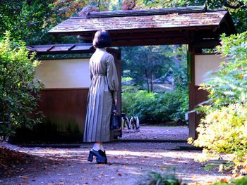 Rear view of woman walking by building