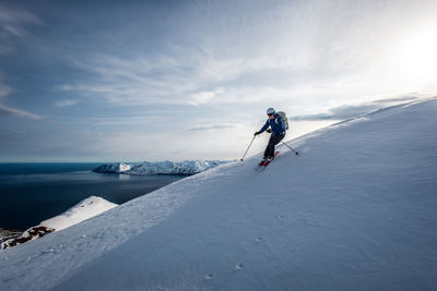 A man skiing downhill with ocean in the background in iceland