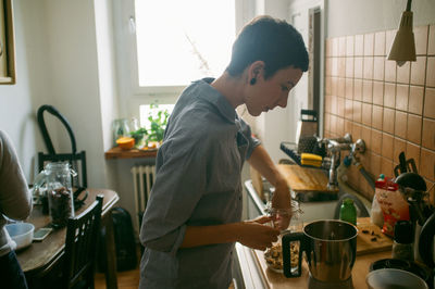 Side view of woman cooking in kitchen at home