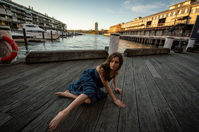 Portrait of woman sitting on wood against sky