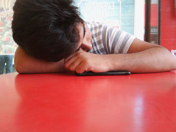 Close-up of teenage boy leaning on red table