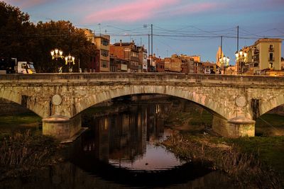 Arch bridge over river in city against sky