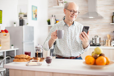 Man drinking coffee cup while standing at kitchen