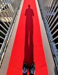 Low section of person standing on red shadow