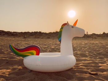 Toy on beach against sky during sunset