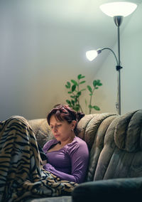 Woman looking away while sitting on sofa