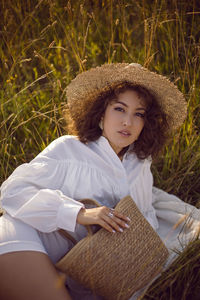 Portrait of young woman sitting on field