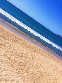 Scenic view of beach against clear blue sky