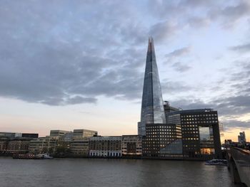 Low angle view of skyscrapers against cloudy sky