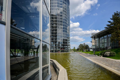 Modern buildings by river in city against sky