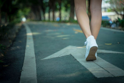 Low section of woman walking on road