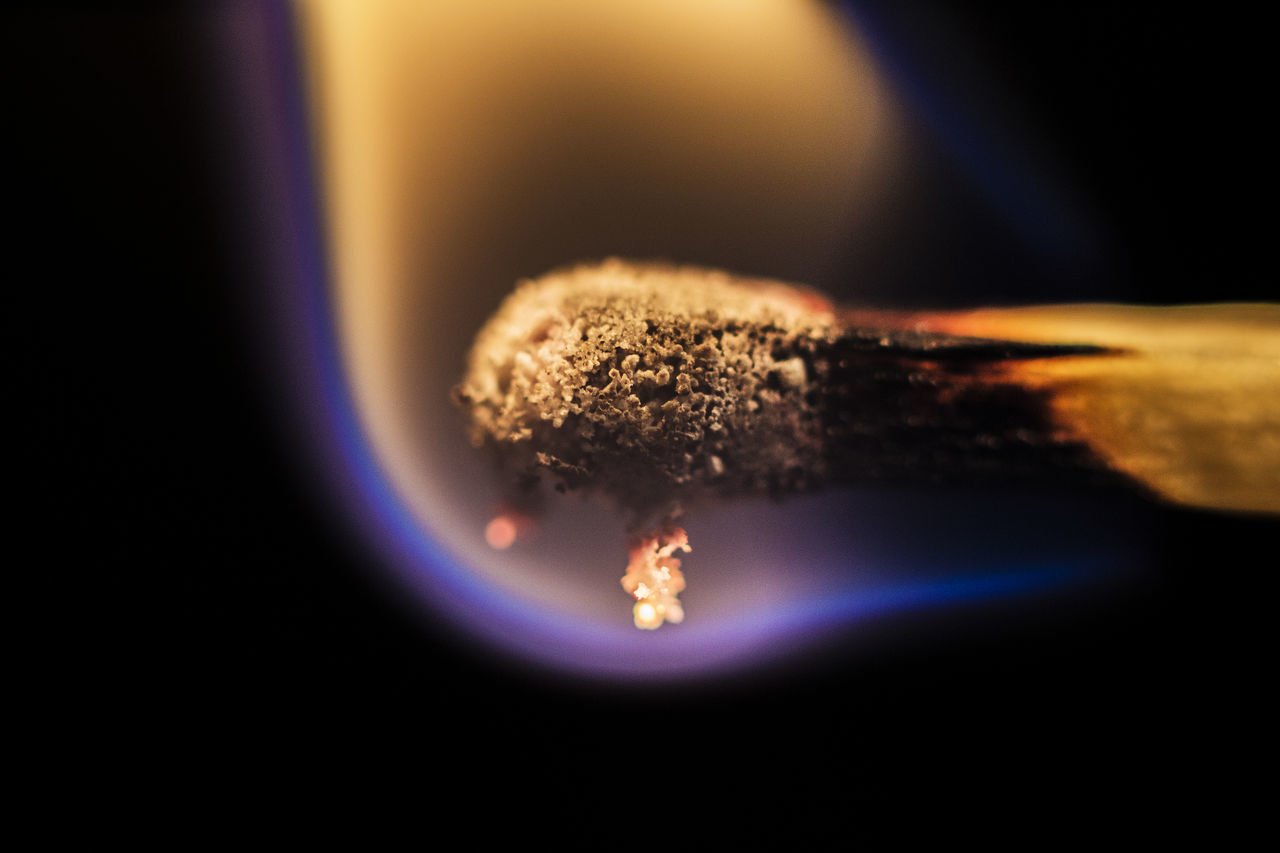 CLOSE-UP OF ILLUMINATED CIGARETTE IN BLACK BACKGROUND