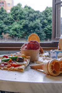 Front view of salty crepe and ice cream tubs on marble table in front of a window