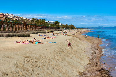 People relaxing on beach against sky