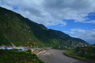 Scenic view of river by mountains against sky