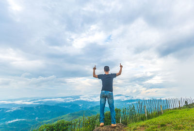 Full length of man looking at green landscape against sky