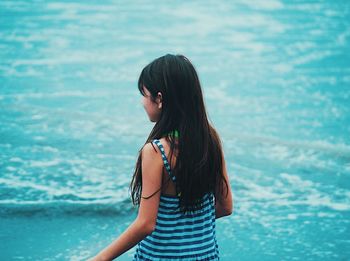 Woman standing in swimming pool against sea