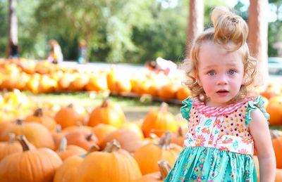 Portrait of shocked girl standing pumpkins at park during autumn