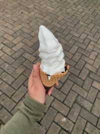 Midsection of person holding ice cream on cobblestone street