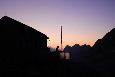 Silhouette houses and buildings against sky during sunset